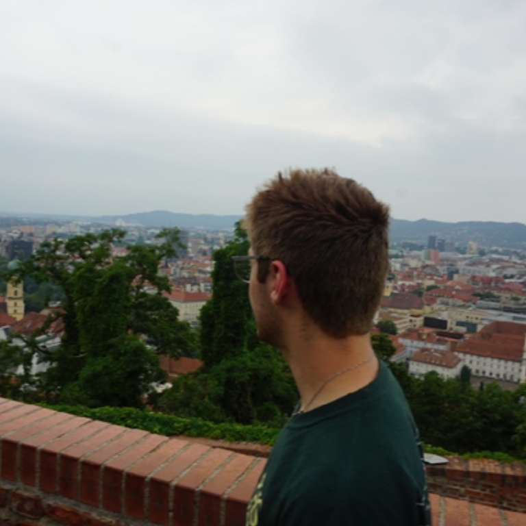 A student is viewed from behind as he looks over a balcony onto a city