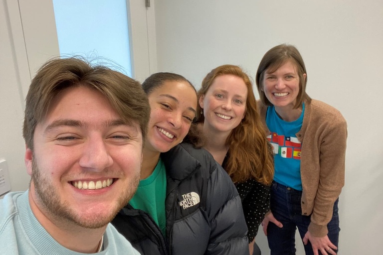 The IUHPFL office team stands in a layered row while smiling at the camera in a selfie photo