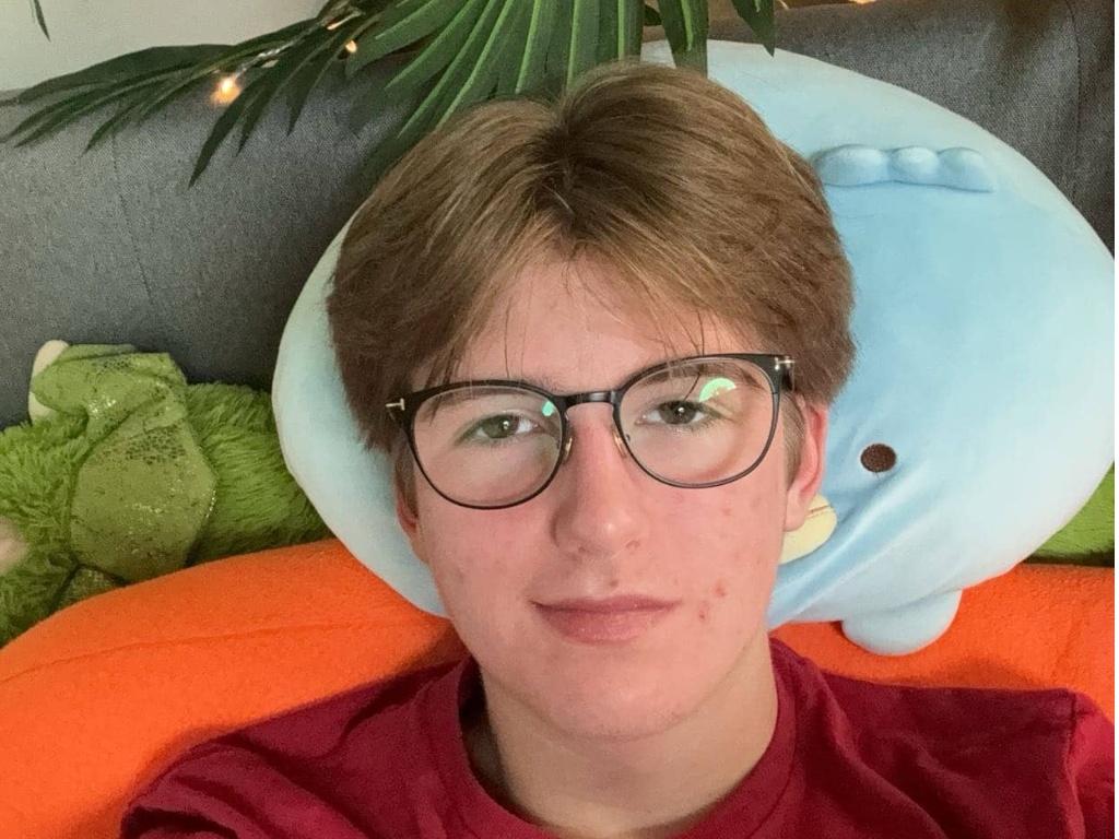 Selfie taken by a student lying on a couch with plants and twinkle lights in the background