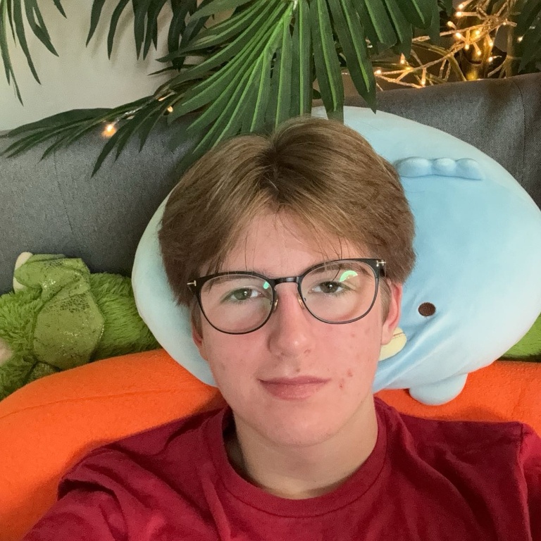 Selfie taken by a student lying on a couch with plants and twinkle lights in the background