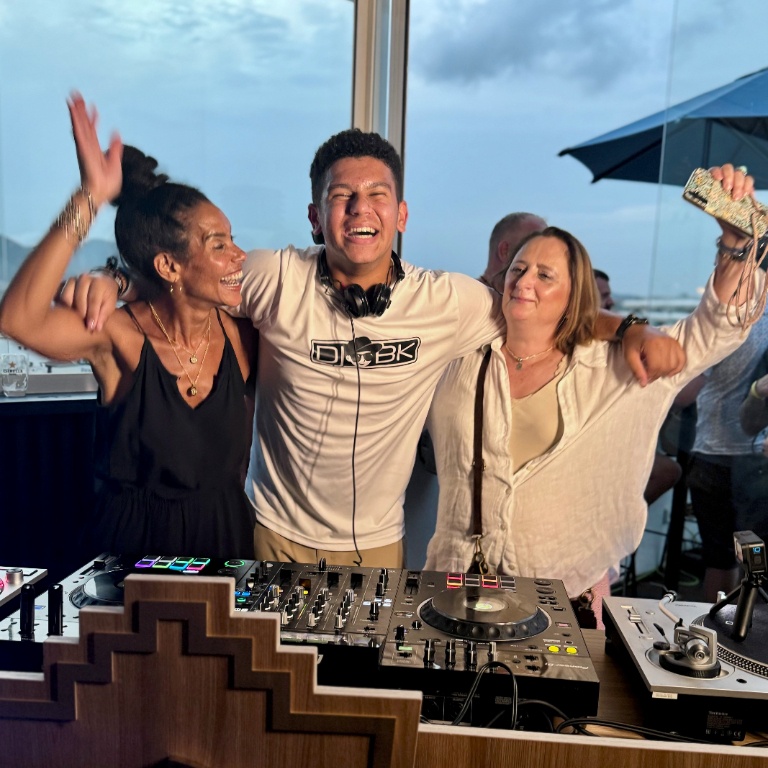 A student poses with two women on either side of him while DJing