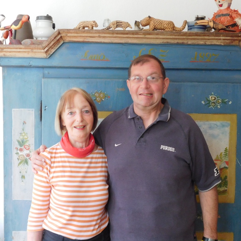 Two adults pose in front of a blue piece of furniture