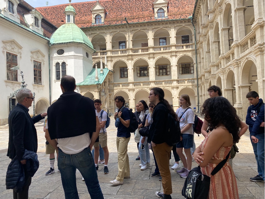 Students stand in a courtyard while listening to a tour guide