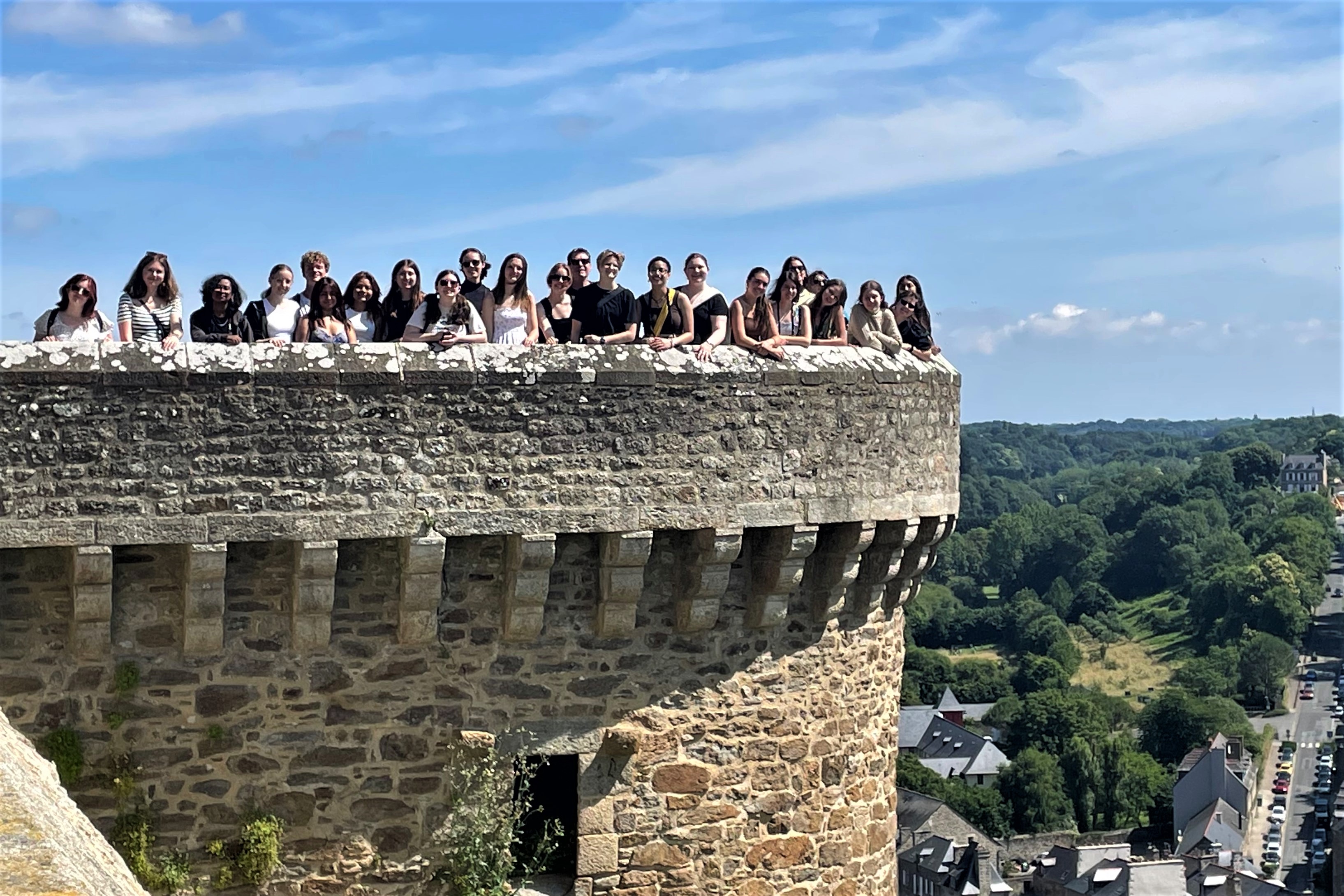 A group of students stand on the parapet of a castle