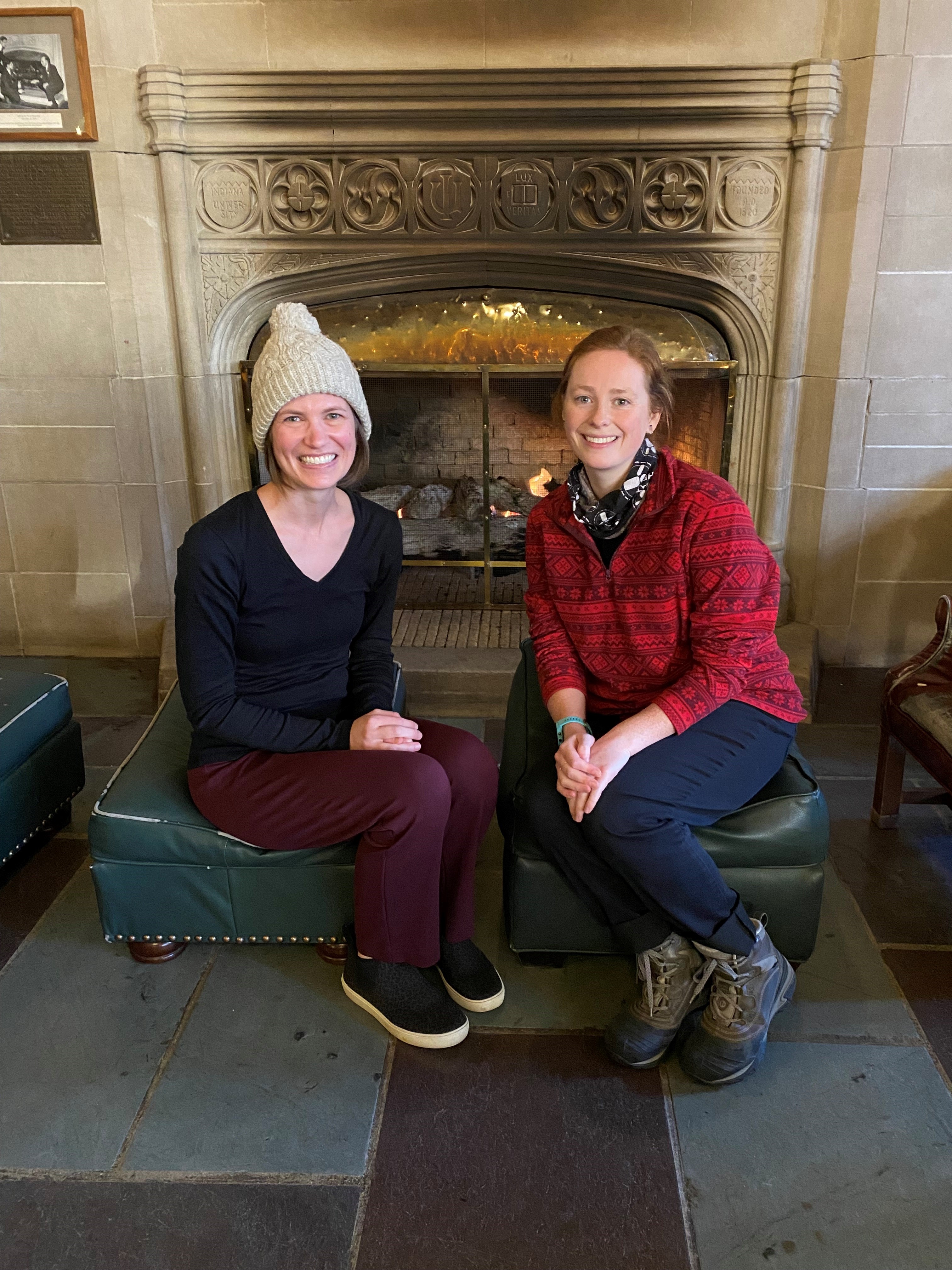 Megan and Anneliese sitting in front of a fireplace
